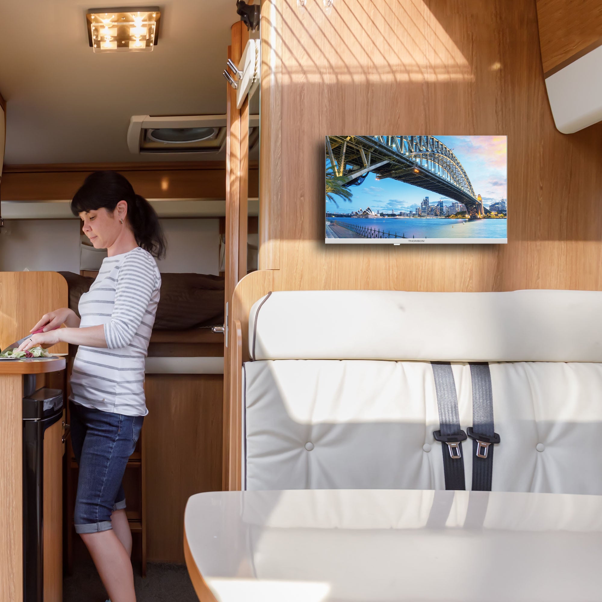 Woman in a caravan with a TV displaying a cityscape.