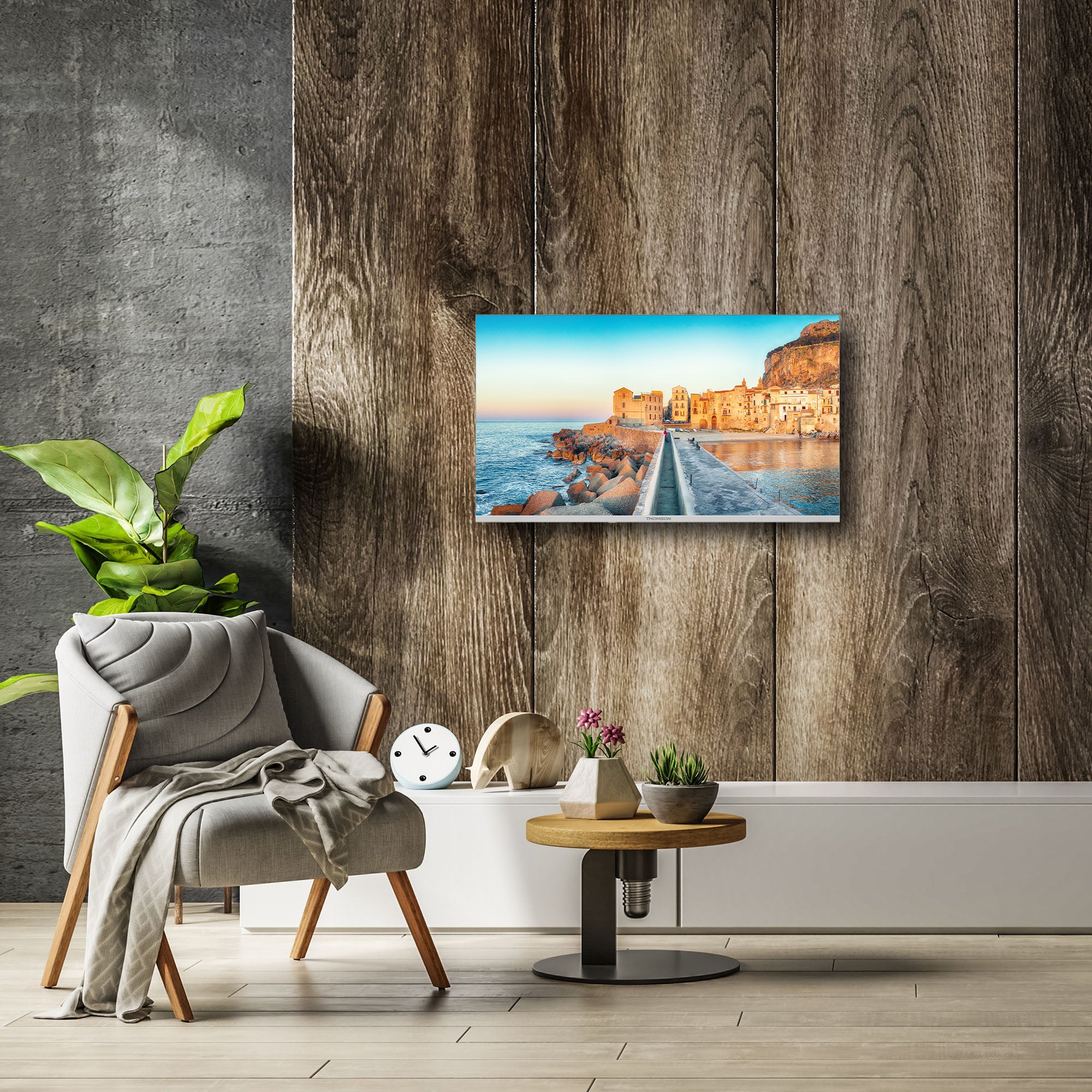 Modern living room with a chair, table, and decorative items against a wooden wall with Thomson TV mounted on the wall a scenic screen fill.